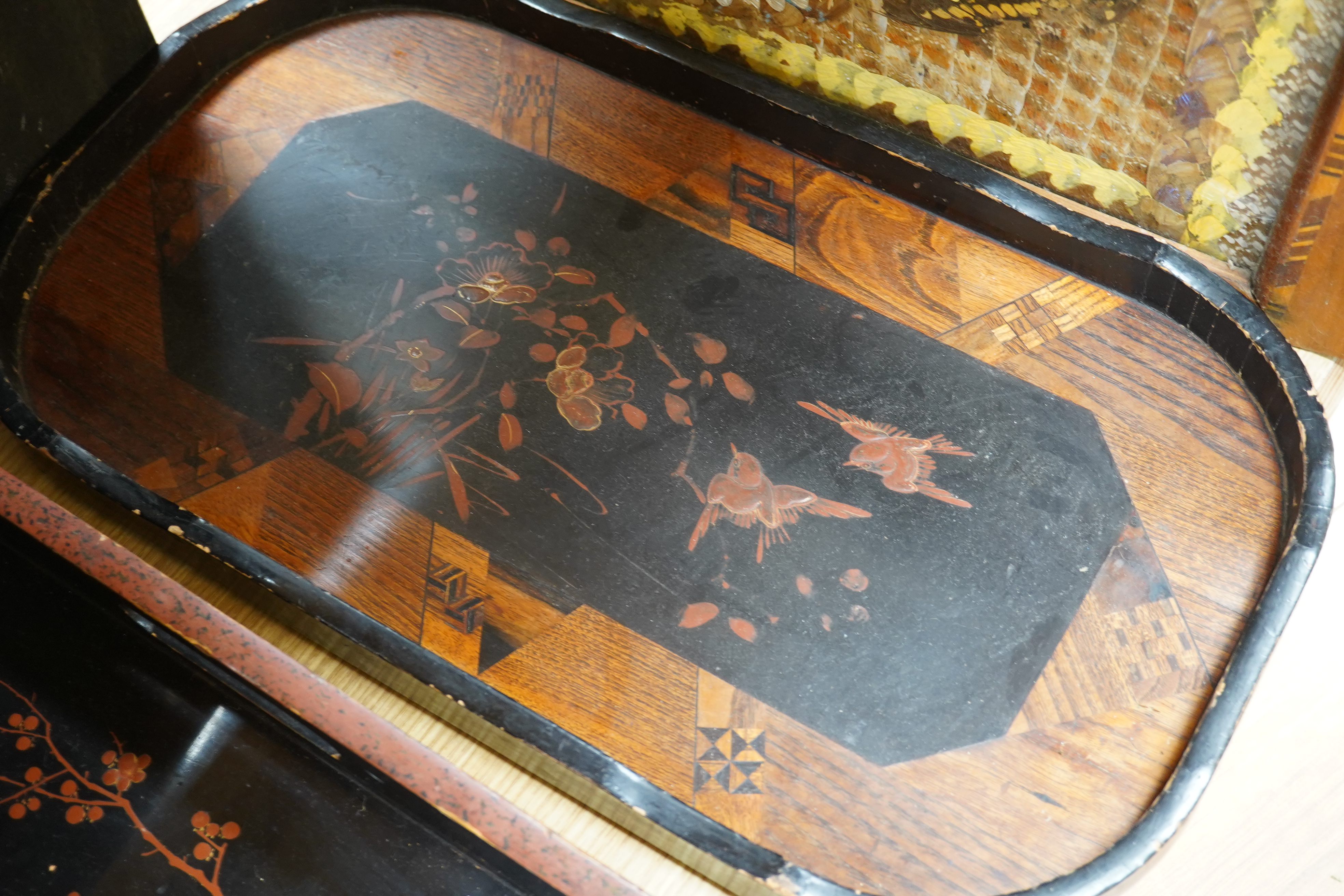 Three trays to include a butterfly wing example and a Japanese lacquered example decorated with birds and flowers, 75cm wide. Condition - poor to fair